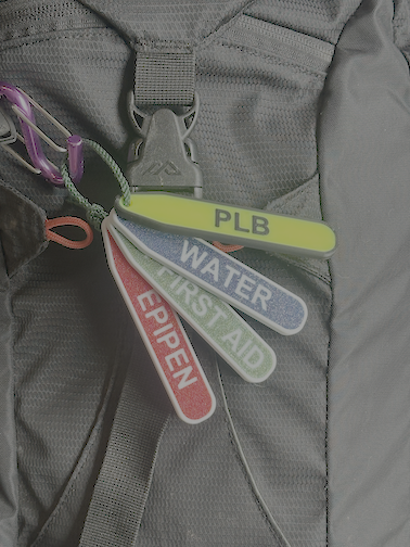 PackAlert tags on a backpack — PLB, Water, First Aid, EpiPen labels